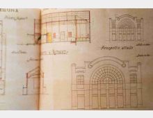 Pagina di un quaderno con disegni tecnici architettonici che mostrano sezioni e prospetti di una facciata con grande arco e finestrature, con annotazioni e scala indicate. I tratti sono a matita e inchiostro su carta ingiallita, con la piega del libro visibile al centro.